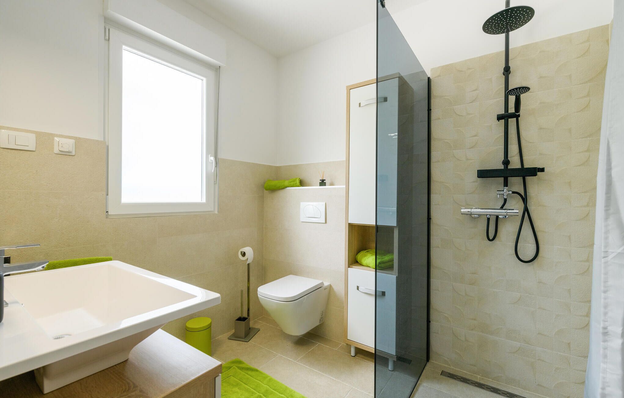 A modern bathroom with a glass shower enclosure, a white sink, and a toilet.