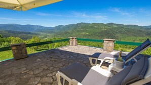 A stone patio with lounge chairs and a table, overlooking a mountainous landscape. - 4 bedroom cozy home in Podstene (Podstene)
