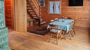 A wooden interior with a dining table, chairs, a staircase, and a TV mounted on the wall. - 4 bedroom cozy home in Podstene (Podstene)