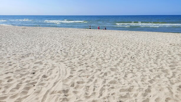 Une vaste plage de sable fin, avec des vagues douces et un ciel dégagé.