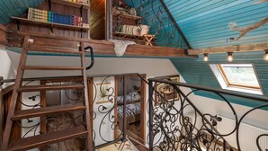 Una habitación estilo loft con una escalera de madera, una cama en zona alta y una estantería llena de libros.