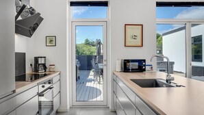 Una cocina moderna con un ventanal grande, una cafetera y un microondas.