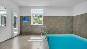 Zona de piscina con vista despejada al exterior a través de una ventana, una escalera metálica y suelo de baldosas.