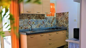 A kitchen with patterned tiles, wooden cabinets, and a colorful rug.