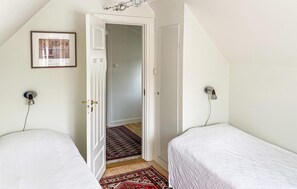 A bedroom with two beds, a door leading to another room, a wall-mounted light fixture, and a framed picture. - Lovely home in Visby with WiFi (Visby)