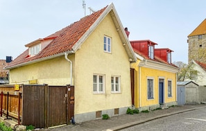 A two-story building with a red-tiled roof, a yellow facade, and a wooden gate. - Lovely home in Visby with WiFi (Visby)