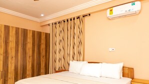 Een slaapkamer met een houten kledingkast, een bed met witte beddengoed en een airconditioning op de muur.