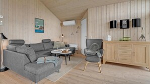 A modern living room with a grey sofa, a grey armchair, a small round table, and a wooden cabinet. - Stunning home in Lemvig with WiFi (Lemvig)