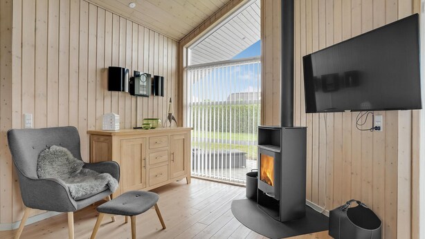 A modern living room with a fireplace, wooden walls, a TV, and a cozy seating area. - Stunning home in Lemvig with WiFi (Lemvig)