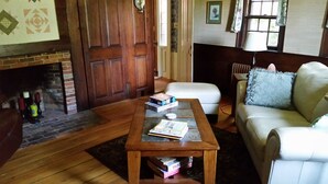 A cozy living room with a fireplace, a wooden coffee table with books, a white sofa, and a window with curtains. - Fabulous, restful, studio with AC in charming Hopkinton (Hopkinton)