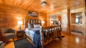 A wooden cabin bedroom with a bed, nightstands, a chair, and a mirror.