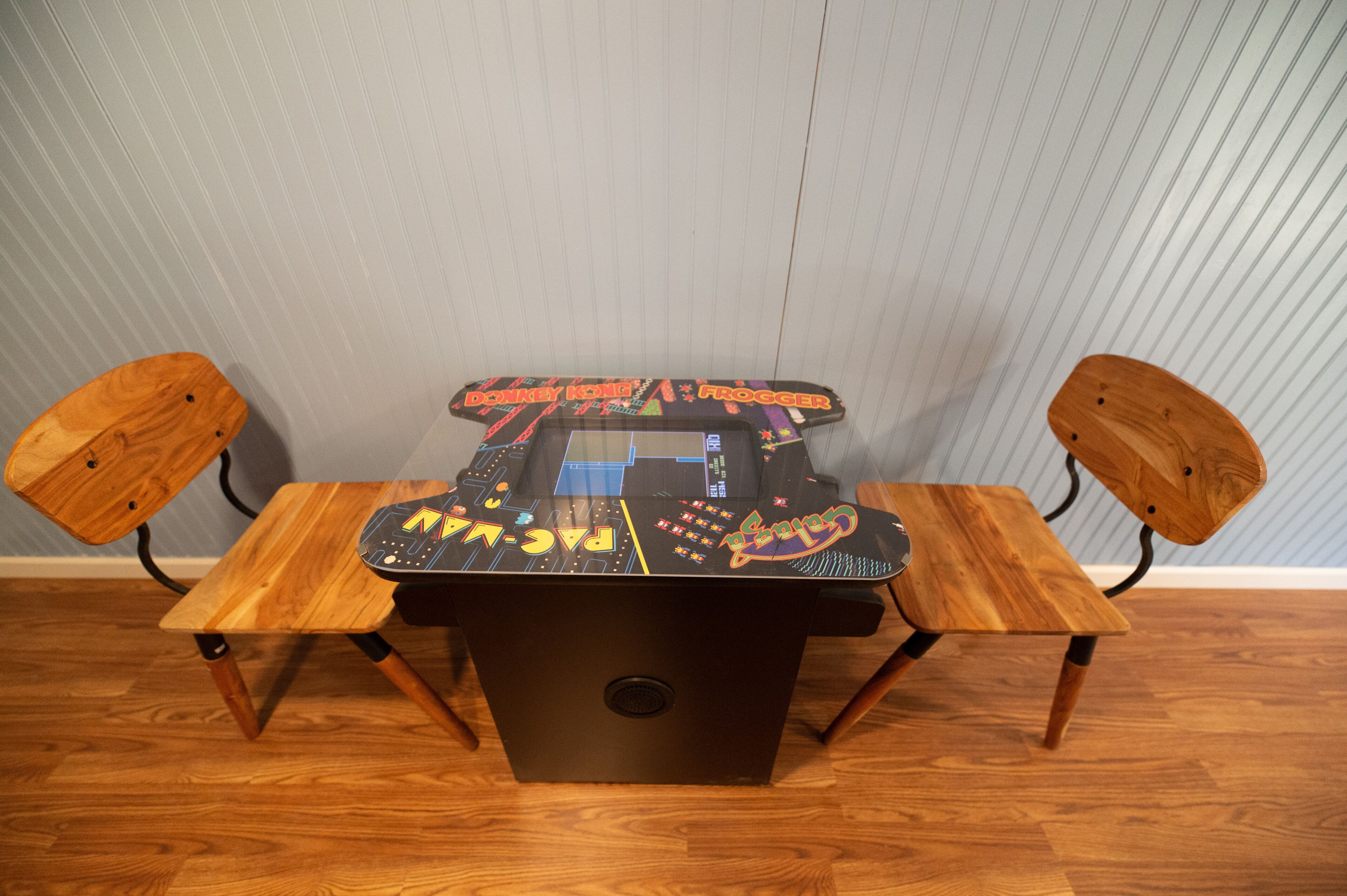 A wooden table with a black electronic device on top, flanked by two wooden chairs.