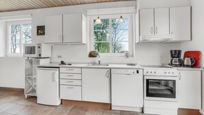 Eine moderne Küche mit weißen Schränken, einem eingebauten Ofen, einer Mikrowelle und einer Kaffeemaschine.