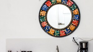 A bathroom with a white sink, a mirror with colorful patterns, and a coffee maker. - Brisa Del Mar (Isla Holbox)