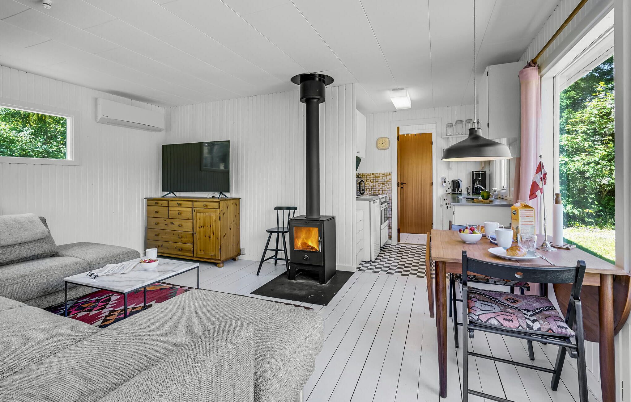 Ett mysigt vardagsrum med en soffa, ett träskåp, en tv och en öppen spis.