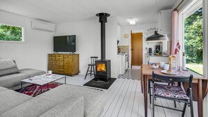 A cozy living room with a sofa, a wooden cabinet, a TV, and a fireplace. - 1 bedroom nice home in Eskebjerg (Eskebjerg)