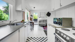 A modern kitchen with a checkered floor, a stove, and a dining area with a sofa. - 1 bedroom nice home in Eskebjerg (Eskebjerg)