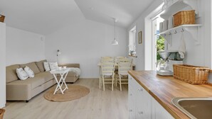 Une cuisine moderne avec des meubles blancs, un plan de travail en bois et des paniers en osier.