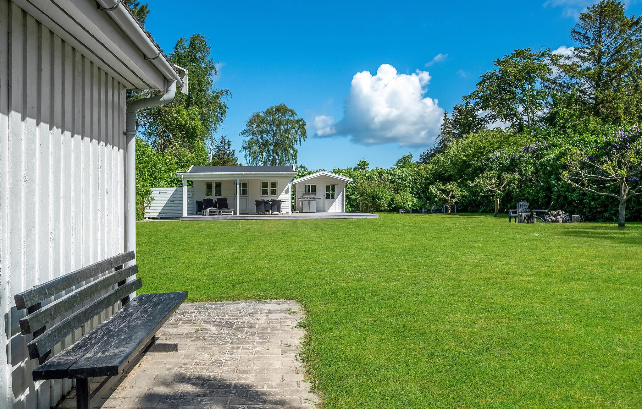 En vit byggnad med en veranda och en liten tillbyggnad.