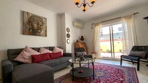 A living room with a sofa, a coffee table, a Buddha statue, and a view through a sliding glass door. - Awesome apartment in Torrevieja with WiFi (Torrevieja)