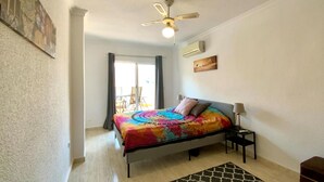 A bedroom with a bed, a ceiling fan, a nightstand, a lamp, and a view of the outside. - Awesome apartment in Torrevieja with WiFi (Torrevieja)