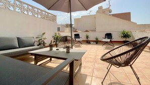 A rooftop patio with a sofa, chairs, a table, and an umbrella. - Awesome apartment in Torrevieja with WiFi (Torrevieja)
