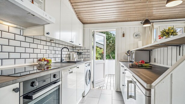 Une cuisine moderne avec des meubles blancs, un four encastré et un lave-linge.