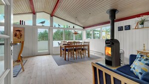 Une pièce spacieuse avec un plancher en bois, un coin repas avec des chaises, un canapé et un poêle à bois.