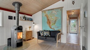 Un salon chaleureux avec un poêle à bois, une grande carte accrochée au mur, un canapé et un buffet en bois.