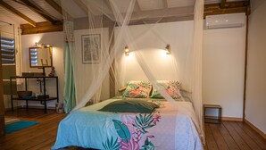 Une chambre à coucher avec un lit à baldaquin, un plancher en bois, une table de chevet et une commode.