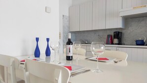 Une table à manger dressée avec des verres à vin, une bouteille de vin et des vases bleus.