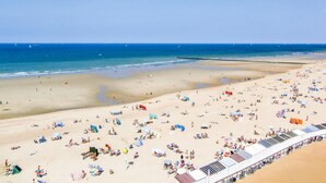 Une plage dotée de nombreuses chaises longues et de parasols, une longue jetée où l’on peut faire du vélo, et une vue dégagée sur l’océan.