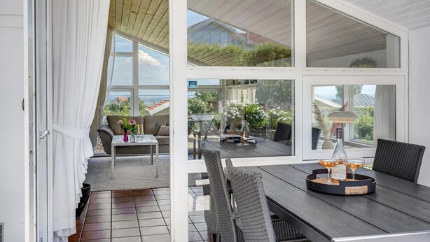 An open-plan living area with a dining table, chairs, and a view of the garden and sea. - Pet friendly home in Sjølund with sauna (Sjølund)
