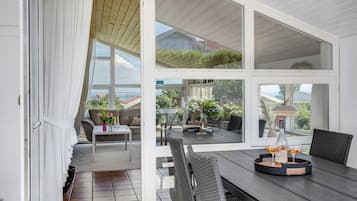 Un espace de vie ouvert comprenant un coin repas avec une table, des chaises et une vue sur le jardin et la mer.