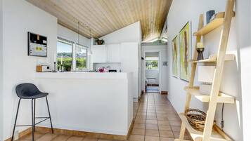 Une cuisine moderne dotée d’un îlot central, d’un coin bar et d’une étagère en bois en forme d’échelle.