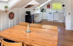 A cozy kitchen with white cabinets, a wooden dining table, and a fireplace. - Pet friendly home in Hvide Sande with sauna (Hvide Sande)