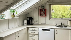 A compact kitchen with a dishwasher, coffee maker, and a window with a view of greenery. - Pet friendly home in Hvide Sande with sauna (Hvide Sande)