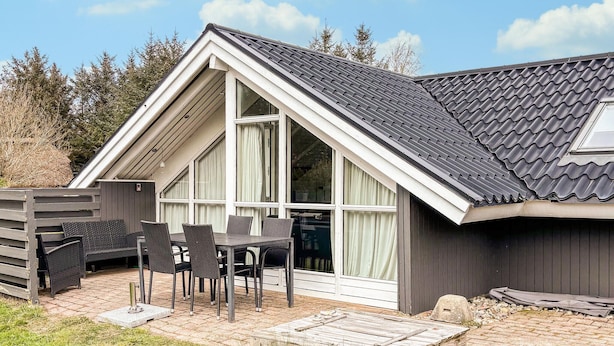 A house with a sloped roof, large windows, and a patio with outdoor furniture. - Pet friendly home in Hvide Sande with sauna (Hvide Sande)