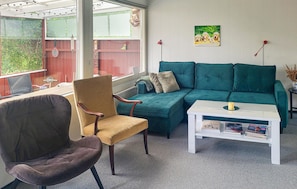 Una sala de estar con un sofá verde, un sillón marrón y una mesa de centro blanca.
