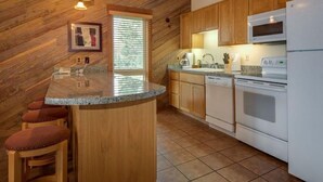 A kitchen with wooden cabinets, a granite countertop, and a bar area with stools. - Best Location and layout at 7th Mountain 1024 SF 2 Bed/2 Bath - Pet Friendly (Bend)