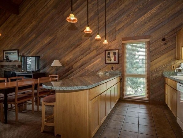 A kitchen with wooden cabinetry, a granite countertop, and pendant lighting.