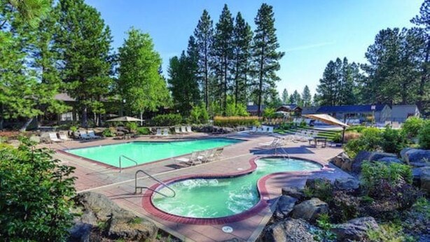 A swimming pool area with a hot tub, lounge chairs, and a rocky landscape. - Best Location and layout at 7th Mountain 1024 SF 2 Bed/2 Bath - Pet Friendly (Bend)