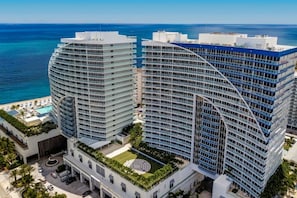 Een hoog hotel met meerdere verdiepingen, een zwembad op het dak en uitzicht op de oceaan.