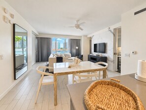 A modern hotel room with a dining area, a flat-screen TV, and a view of the city.