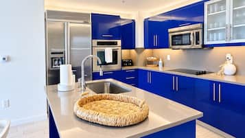 A modern kitchen with blue cabinets, stainless steel appliances, and a central island with a woven basket.