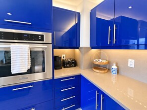 A modern kitchen with blue cabinets, a stainless steel oven, and a toaster.