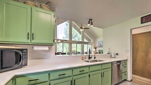 A kitchen with green cabinets, a microwave, a sink, and a dishwasher. - 'The River Home' Cabin w/ Yard: Near Wolf Creek! (Pagosa Springs)