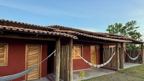 Une rangée de portes en bois, un mur rouge, un hamac et un ciel dégagé.