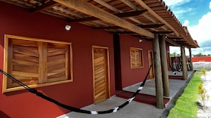 Un bâtiment à la façade rouge, doté de portes en bois et d’une pergola en bois.