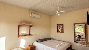 Une chambre comprenant un lit, un bureau, une chaise, un ventilateur de plafond, un appareil de climatisation et une fenêtre donnant sur un paysage agréable.